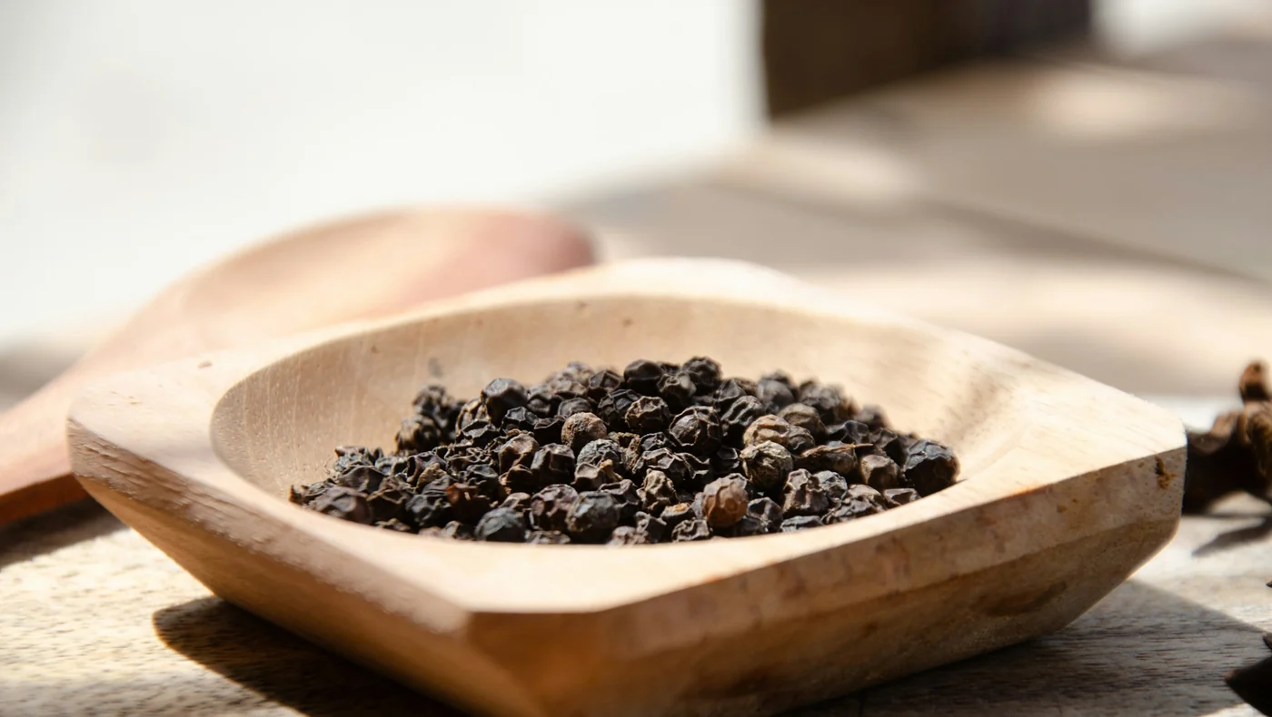 Pebre negre en gra dins d'un bol de fusta